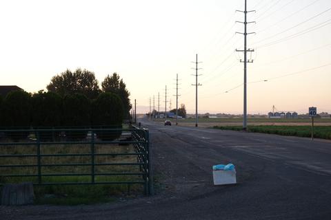 A yard sale sign with large powerlines in the background.